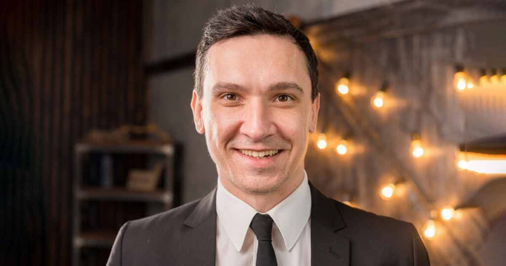A smiling man in a suit and tie, showcasing a polished headshot with professional retouching.
