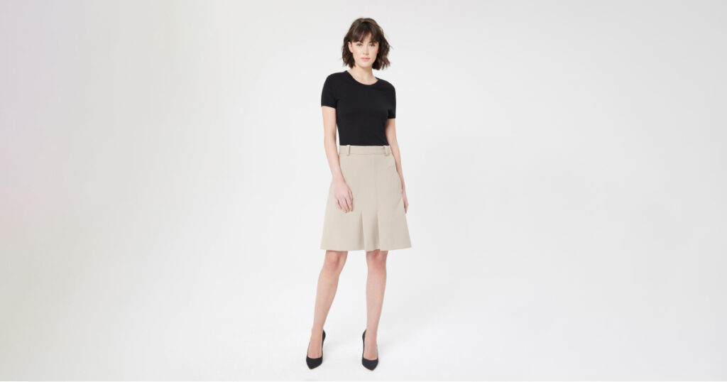 A woman wearing a black top and skirt poses confidently, showcasing model photo retouching techniques.